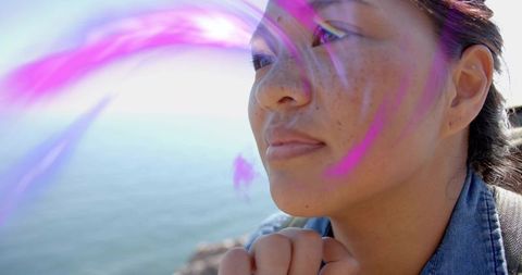 Asian Woman with Backpack Contemplates by Rocky Shore with Purple Light