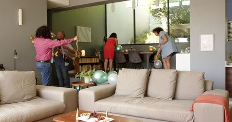 Diverse Friends Preparing for Indoor House-Warming Celebration