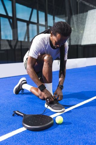 Active man prepares for padel match on blue court