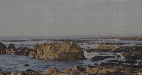 Golden-hour rocky coastline featuring sandstone boulder and tidal pools at low tide