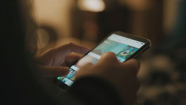 Close-up hands tapping and scrolling smartphone screen under warm indoor lamp light