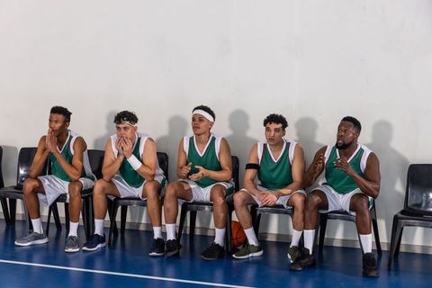Basketball team sitting on sidelines awaiting gameplay