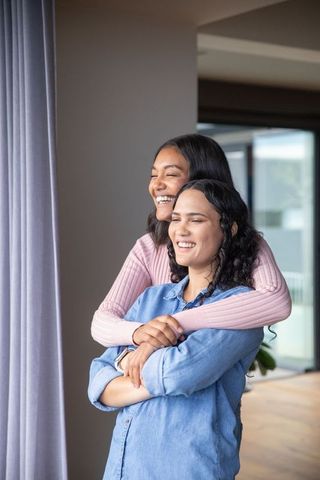 Affectionate Hug Between Two Women in Bright Living Room