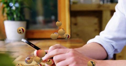 Person Using Smartphone with Floating Emojis in Modern Workspace