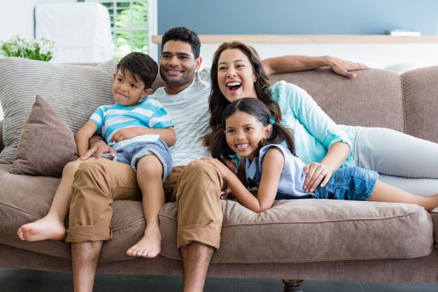 Happy parents and kids sitting on sofa in living room at home