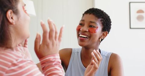 Friends enjoying under-eye patches and bright conversation during cozy skincare moment