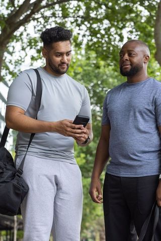 Two african american men checking phone outdoors after workout