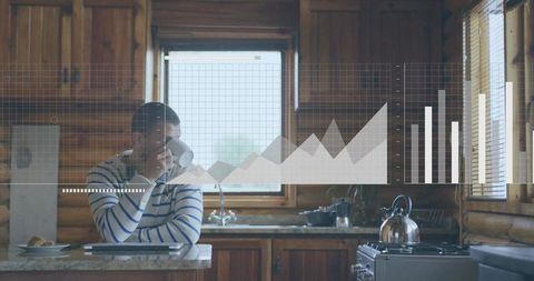 Sitting adult male sipping coffee in rustic cabin kitchen with digital analytics overlay