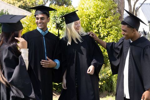Diverse Graduates Celebrating on Campus Lawn in Gowns