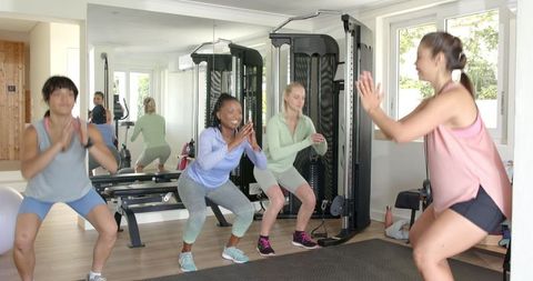 Multiracial Women Exercising in Home Gym with Fitness Trainer