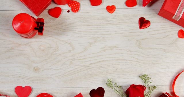 Romantic Valentine's Day decorations arranged on a light wooden background. Featuring red hearts, gift boxes, roses, candles, and holiday decor, this image exudes festive romance. Ideal for use in Valentine's Day promotions, romantic event invitations, or holiday marketing materials.