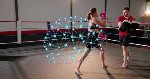 Woman boxer training with coach holding pads, motion-tracking overlay showing technique analytics