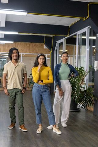 Young diverse professionals standing in modern open office, casual teamwork and collaboration