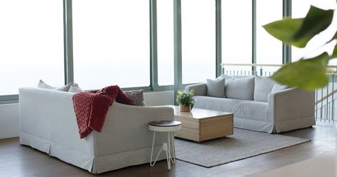 Minimalist bright living room featuring light-gray sofas, red throw and large windows