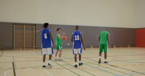 Basketball players practicing passing drill on indoor court showing teamwork and training