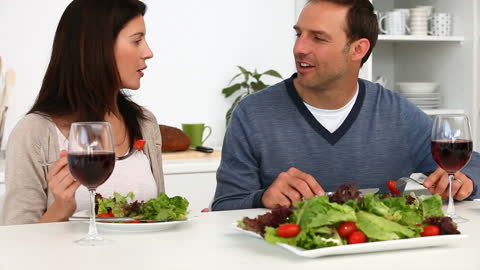 Couple Enjoying Salad and Wine at Kitchen Table