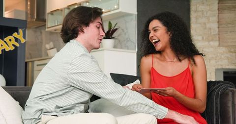 Joyful Couple Exchanging Gifts During Anniversary Party at Home