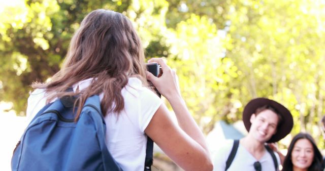 Young Female Tourist Photographing Friends Outdoors in Sunny Park - Download Free Stock Images Pikwizard.com