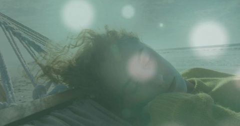Woman relaxing on hammock at peaceful beachfront