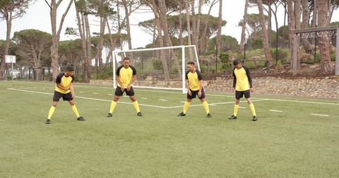 Soccer Players in Yellow Jerseys Performing Warm-ups on Field