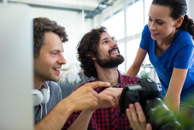 Male graphic designers showing pictures to his coworkers on camera in office