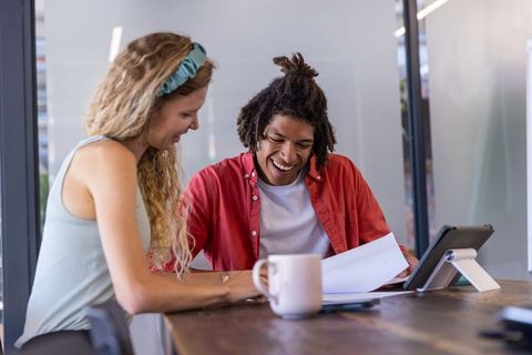 Coworkers Laughing over Document in Modern Office Setting