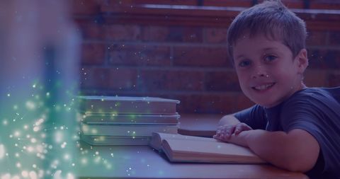 Smiling boy surrounded by magic book glows