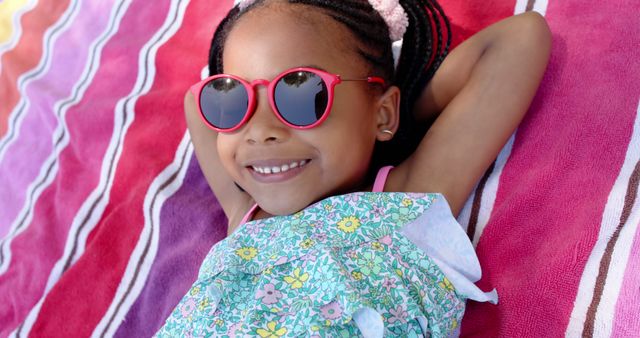 Happy african american girl lying on towel on garden and smiling. Free time, weekend, vacations and summer, unaltered.