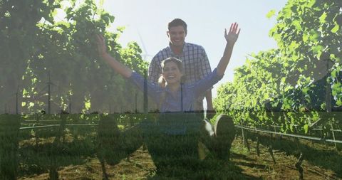 Couple laughing in sunlit vineyard with man giving piggyback ride