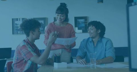 Team collaborating and reviewing documents at table, woman leading discussion in modern office