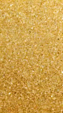 Vertical video capturing closeup gold sequin shimmer with drifting highlights and sparkle