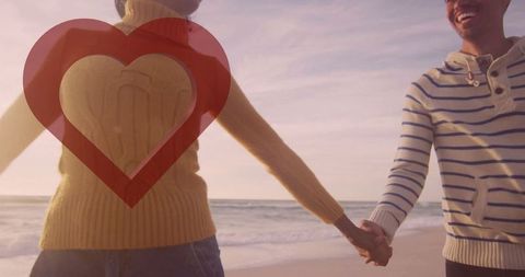 Romantic couple beach walk at sunset with heart overlay
