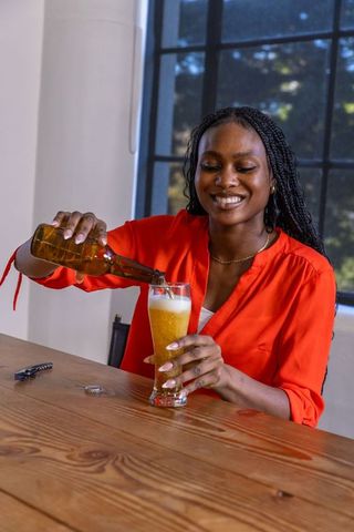 Joyful Woman Enjoying Casual Beer Indoors by Window
