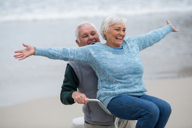Happy senior couple riding bicycle on the beach