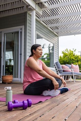 Mature woman practicing gentle porch workout and stretching on purple mat for wellness