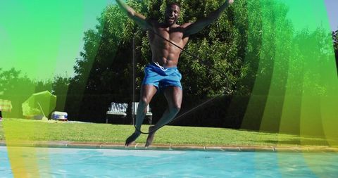 Shirtless man jumping into pool midair with rope backyard summer fitness and joy