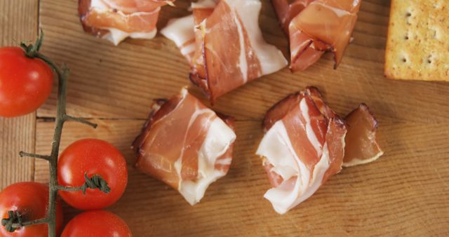 Assorted pieces of ham accompanied by ripe vine tomatoes and crunchy crackers on a wooden board capturing the essence of an easy and stylish appetizer, suitable for culinary blogs, cooking magazines, and food-related advertisements.