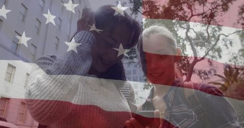 Teenage friends sharing smartphone with american flag overlay outdoors