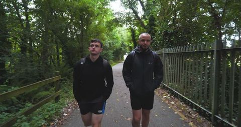 Two men walking on forest path wearing athletic gear