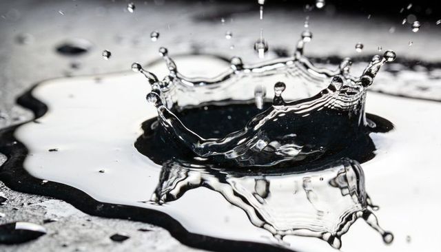 Capturing crown splash creating mirror droplet reflections and ripples on metal surface