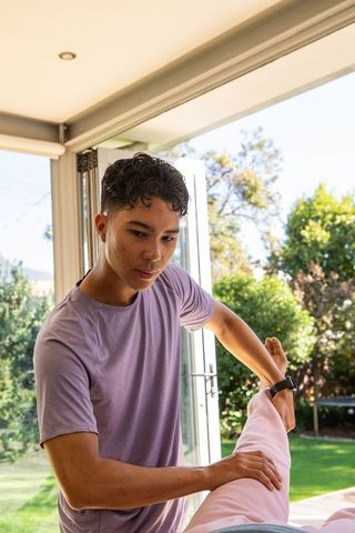 Hispanic Male Personal Trainer Guiding Client in Stretching Routine