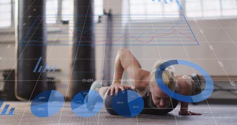 Mid-adult woman pressing medicine ball in gym with fitness hud overlay and analytics