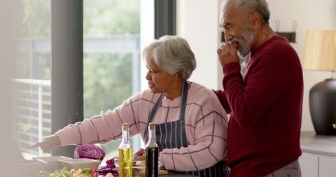 Senior Couple Cooking and Tasting Fresh Ingredients Together in Kitchen