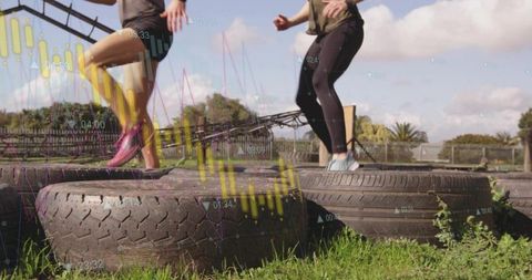 Women exercising on tires with data overlay in sunny outdoors