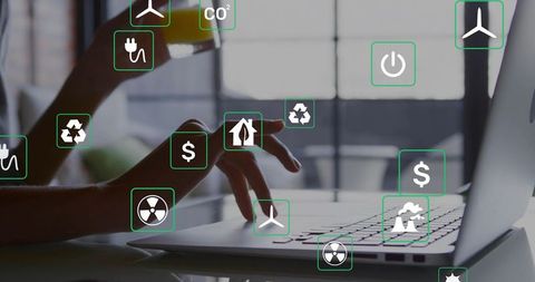 Typing hands on laptop holding smartphone with floating renewable energy and finance icons
