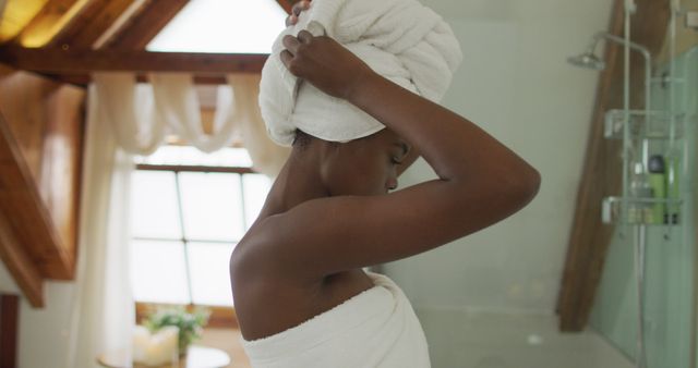 African american attractive woman drying hair with towel in bathroom. beauty, pampering, home spa and wellbeing concept.