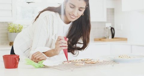 Indian Woman Decorating Festive Cookies in Bright Kitchen