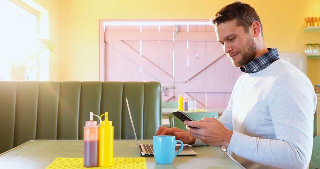 Smiling Man Using Smartphone While Working on Laptop in Cafe - Download Free Stock Images Pikwizard.com