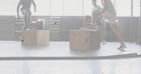 Three athletes performing plyometric box jumps and step-ups in bright gym with daylight