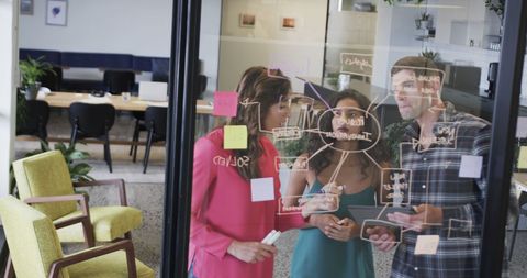 Colleagues Brainstorming with Notes on Glass Board in Modern Office